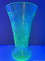 Full view of vase under UV light showing fluorescence and etched pattern