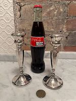 Pair of sterling candlesticks shown beside bottle and coin for scale