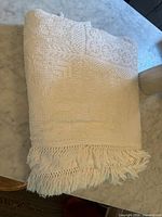 Folded white popcorn knit bedspread showing fringe