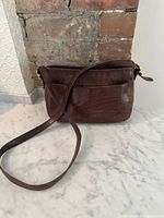 Front of brown Coach purse with strap and exterior slip pocket
