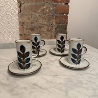 Four mugs each on its saucer displayed on countertop