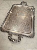 Full view of ornate silverplate tray, showing shape, handles, border and engraved surface