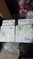 Four square eucalyptus canvas prints with text displayed on round glass table