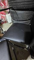 Close-up of seat cushion on one chair showing black faux-leather surface and chrome frame