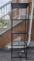 full front view of tall black metal frame shelving unit with mixed material shelves