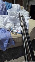 Stack of sheer white, lavender and blue panels with curtain rods and hardware on sofa