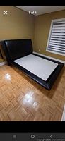 Full view of queen black faux-leather bed frame in room