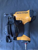 Left side view of Bostitch yellow/black roofing nailer showing magazine and air fitting