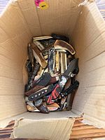 Top view of cardboard box filled with mixed pocket knives
