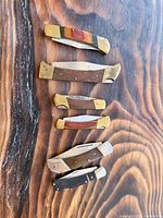 All five folding knives laid out to show size differences, handle materials and blade positions