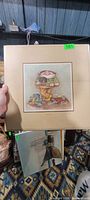 Front view of Kaplan lithograph and some framed pieces behind