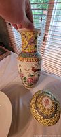 Vase showing floral and bird design with yellow neck plus jar lid nearby