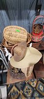 Stack of round and rectangular wicker baskets with two straw hats visible