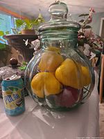 Bulbous ribbed clear glass jar with lid filled with artificial fruit, soda can for scale