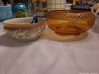 Both bowls side by side: amber pressed glass bowl on right, opaque painted glass bowl on left