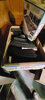 Box with curved black slot car track pieces and packaging