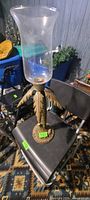 Full view of metal palm candle holder with glass shade on chair