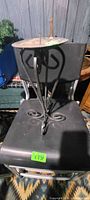 Full view of wrought iron candle stand on chair, showing tripod legs and top plate