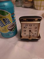 Clock open next to soda can for scale