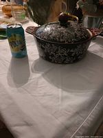 Crock with lid beside soda can for scale