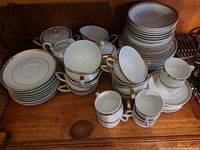 Group of porcelain plates, cups, saucers, sugar bowl and gravy boat on shelf