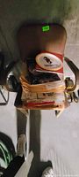 Top view of chair with armrests and stack of ephemera topped by Derby 122 tray