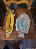Yellow ceramic dish and white platter with clear glass fish dish nested