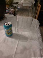 Full view of clear glass dome beside 355 ml soda can for scale