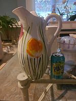 Full view of pitcher alongside soda can for scale