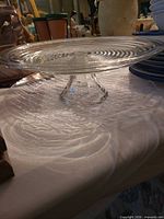 Clear pressed glass pedestal cake stand atop matching platter