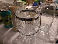 Ice bucket, cylindrical vase and additional glassware on table