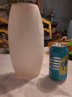 Front view of frosted glass vase beside soda can for scale