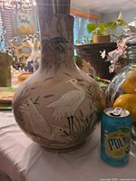 Full view of painted glass vase beside soda can for scale
