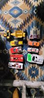 Overview of nine toy vehicles on patterned surface