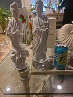 Both porcelain figurines beside soda can for scale
