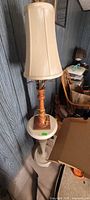 Full view of lamp on pedestal stand against paneled wall