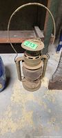 Overall view of metal railroad lantern showing globe, handle, vented top, and worn finish