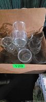 Box containing clear glass carafe surrounded by small clear cups