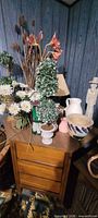 Overview of side table with lamp, bowls, vases, faux plants