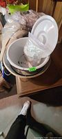 View of stacked aluminum and white enamel bowls with plastic lid and clear bag inside
