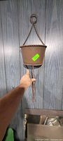 Front view of brown metal hanging planter held against wood panel wall