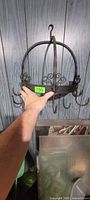 Full view of wrought iron circular pot rack showing hooks and scrollwork
