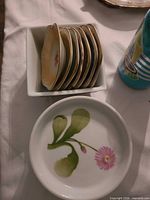 Stack of scalloped square floral plates in bowl beside round floral plate