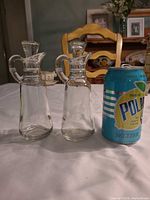 Two clear glass cruet bottles with Polar seltzer can for scale