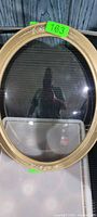 Front view of oval gold picture frame with convex glass