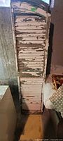 Full view of tall weathered wooden shutter with arched top, white paint heavily flaked