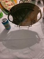 Front view of glazed ceramic platter on stand with soda can for scale