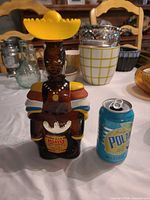 Front view showing entire figural rum bottle next to soda can for scale