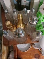 Group view of all salt and pepper shakers showing glass bodies and metal tops, includes gold-tone shaker