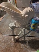 Profile view of cream glass nautilus shell vase beside soda can for scale